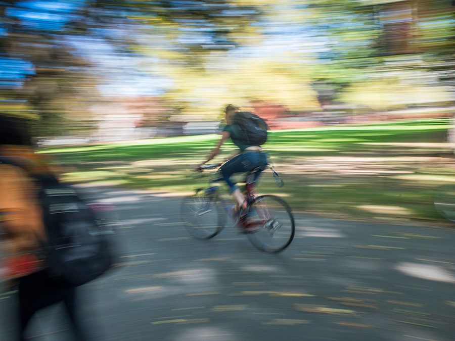 Motion-blurred photo of a student riding a bike on campus