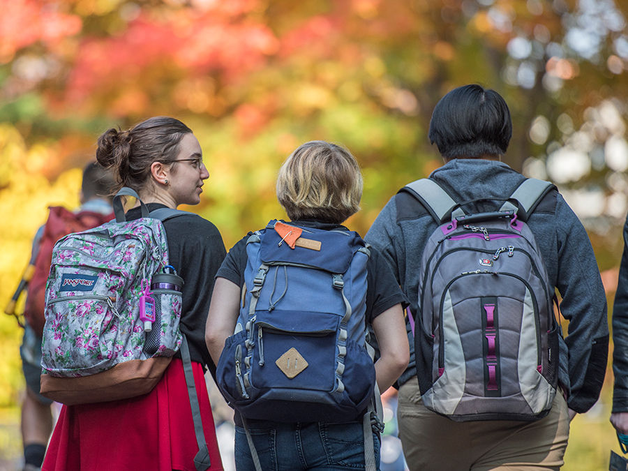 Three students with backpacks walking away from the camera