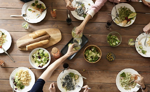 An aerial image of people reaching across a table filled with platters of food.