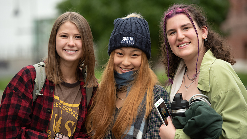 fall campus group scene of three students outside smiling