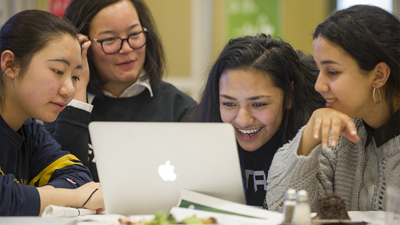 Four students looking at a laptop