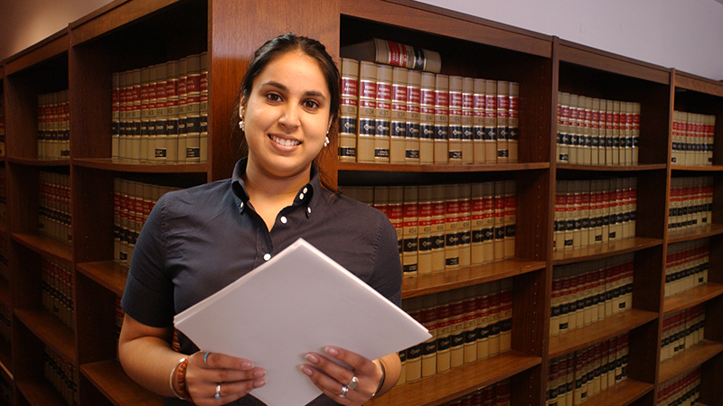 Woman standing in a law library in front of shelves of books