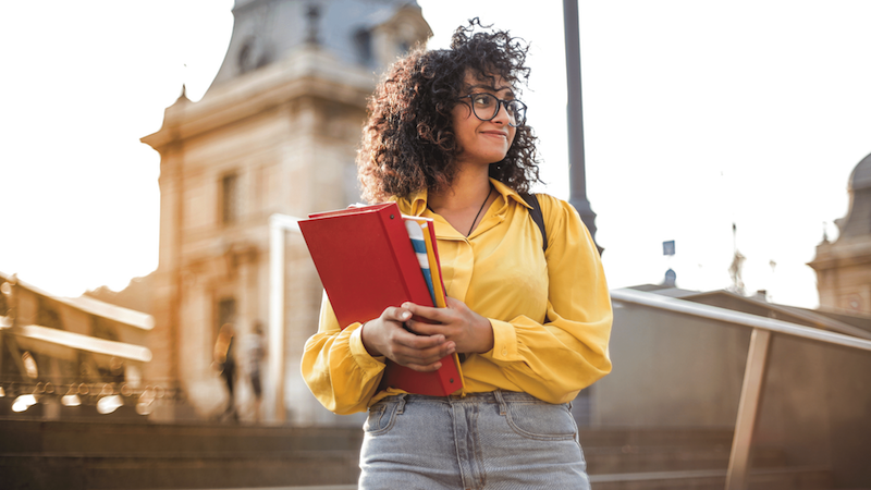 Image of a young woman standing outside holding notebooks