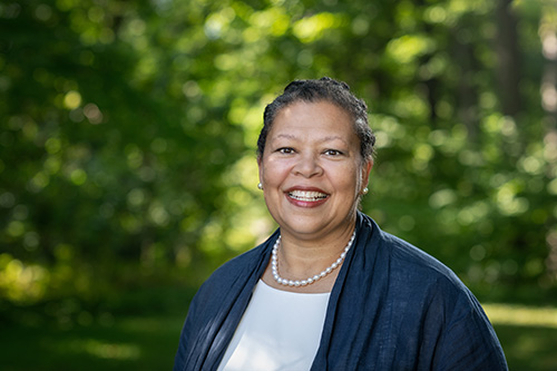 Sarah Willie-LeBreton smiling against a background of green trees.