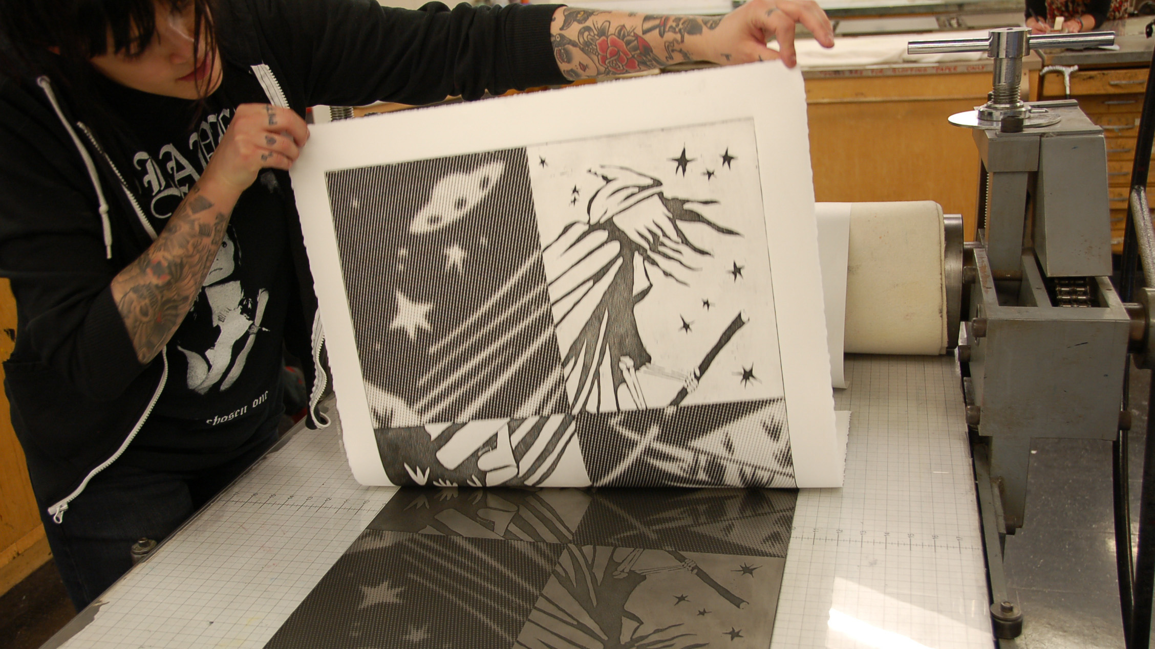 Student holding up an etching in the printmaking studio