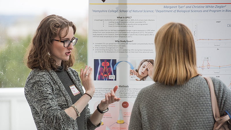 A student discussing a poster to a visitor