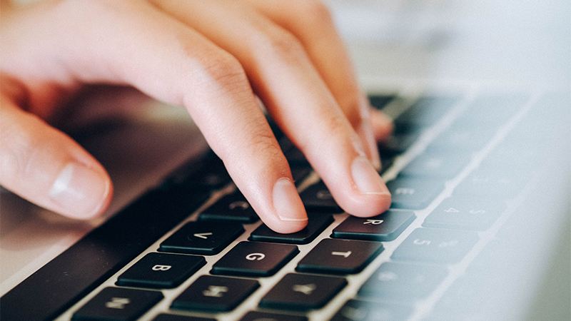 A close-up of a hand typing on a keyboard