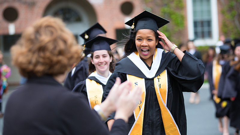 A line of students in caps and gowns marching into Commencement exercises