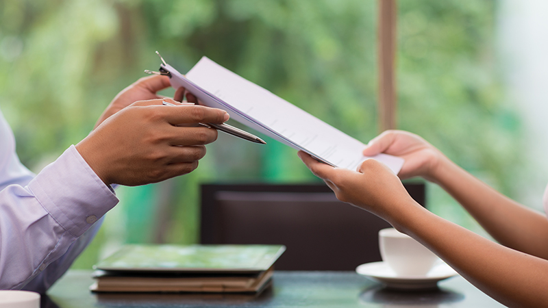 A contract being passed from one person in business attire to another