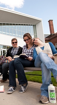 Photo of three students sitting on a bench outside of the Campus Center