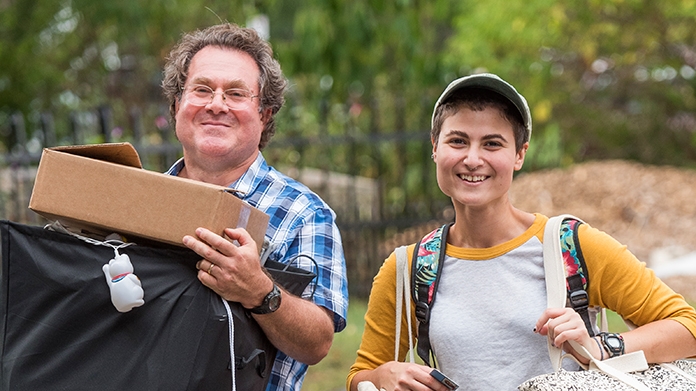 A student and her father carrying boxes into a house