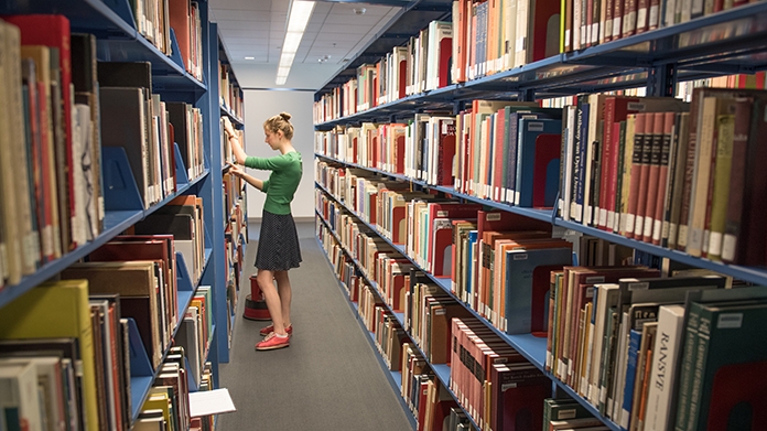 Student browsing the stacks of books in the art library