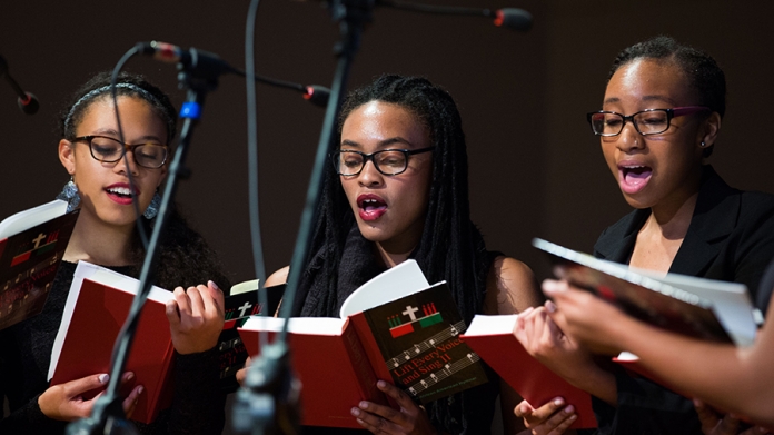 Three students singing in a musical presentation