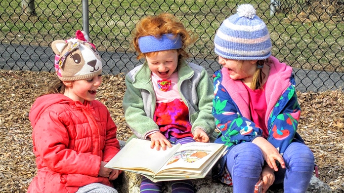 Three girls sharing a book