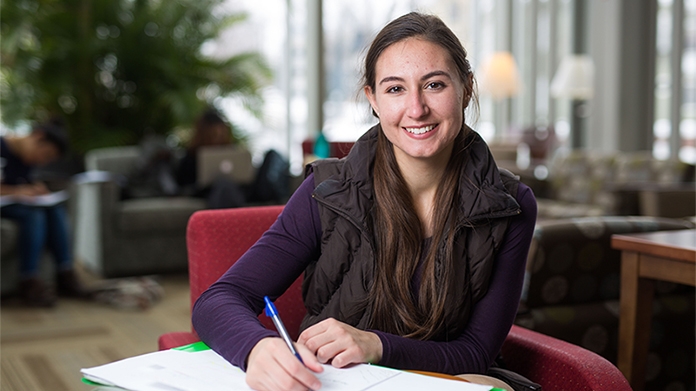 Photo of a smiling student writing in her notebook