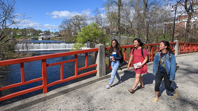 Three students walking across the bridge