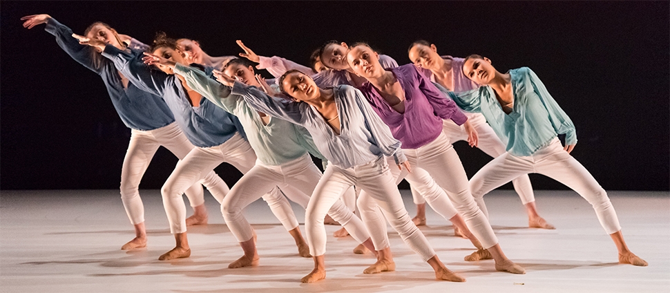 Group of dancers in white pants and differently colored tops