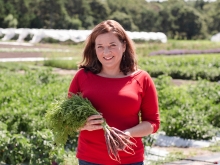 Amy Traverso holding a bunch of carrots outside at a nursery