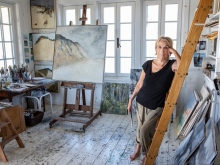 Barefoot Anne Peretz in her studio, surrounded by paintings and easels