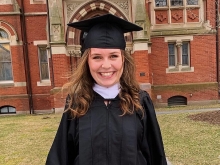 Emma Kemp in a graduation gown under the Grecourt Gate