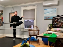 Rodger Blum at a ballet barre with a zoom array of photos on a computer in front of him.