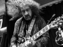 Steve Waksman playing guitar with his long curly hair flying