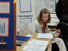 Student studying her notes at her booth during a science fair