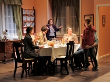 Six actors on stage around a dinner table