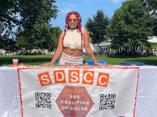 Aushanae Haller '23 stands behind a banner for the SDS Coalition of Color