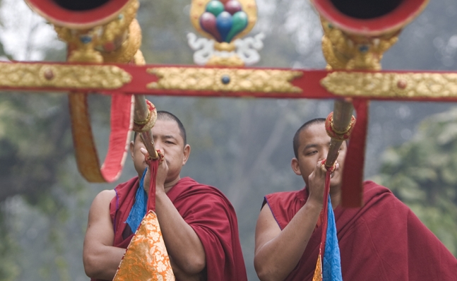 Two monks blowing into large horns, Tibet