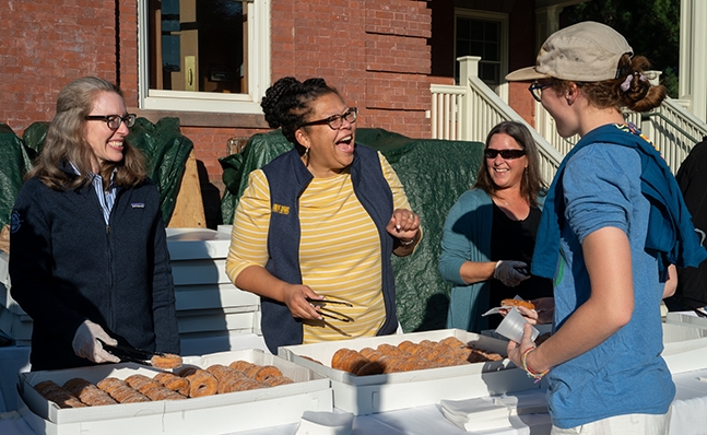 Sarah Willie-LeBreton passing out cider donuts to students on Mountain Day