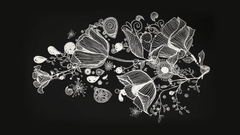 still image taken from a video showing a white floral design on a black background