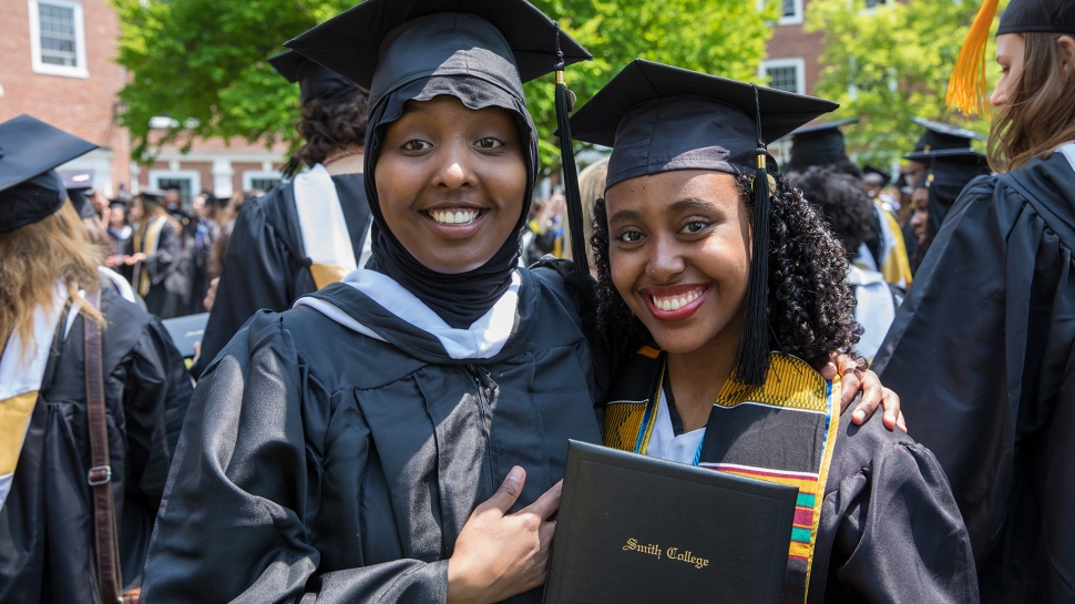 Two graduates holding their diplomas