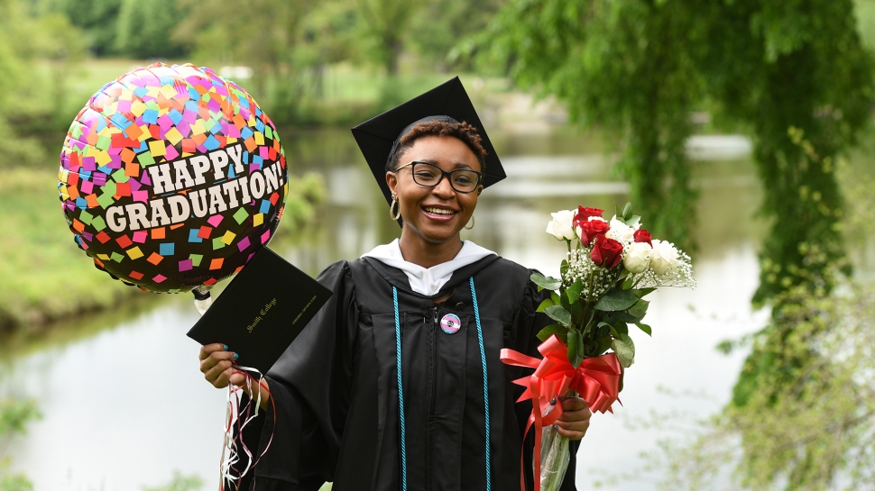 Student in cap and gown, with balloon and flowers
